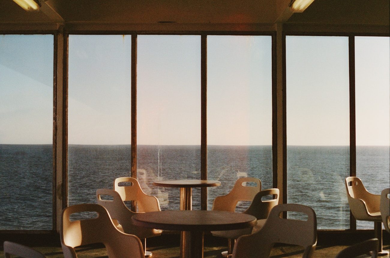 Empty cruise ship café with rows of unused chairs facing the ocean — the quiet evening scene aboard an understaffed cruise ship after the nightly show ends